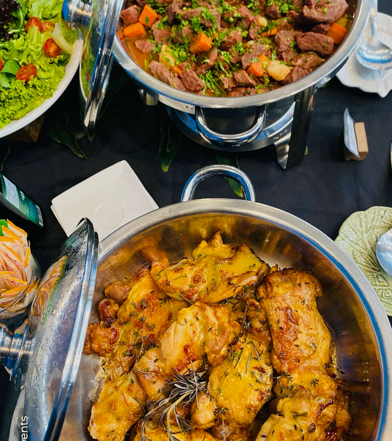 Buffet de almoço corporativo com pratos quentes, carnes e acompanhamentos servido para eventos empresariais
